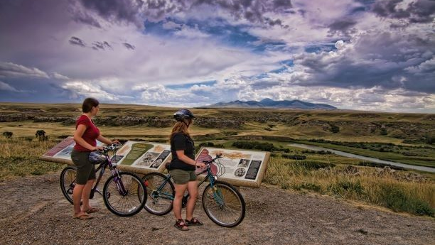Two women on bikes looking over park information.