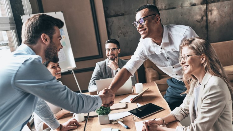 Image of 4 people at a table, handshakes