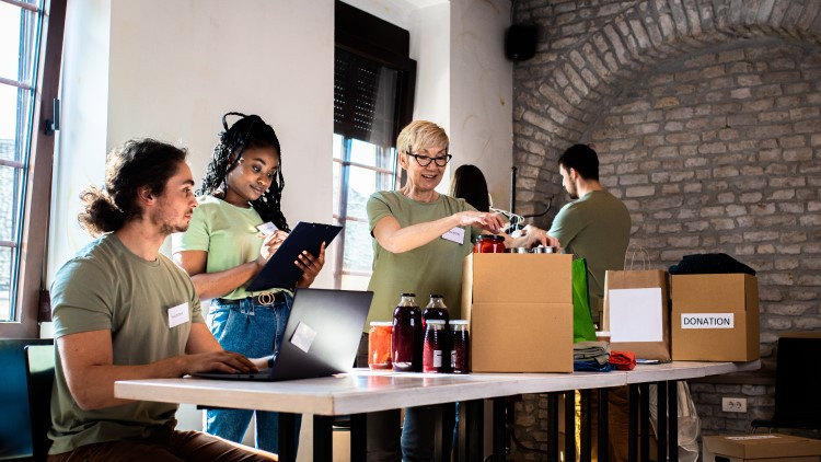 Image of people sitting and 1 person packing a donation box