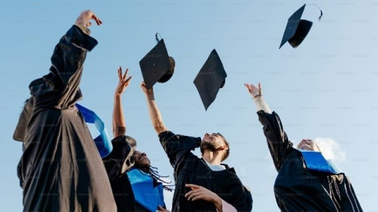 Students in graduation gowns throwing their caps in the air