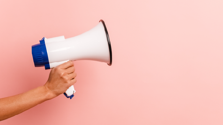 Hand holding blowhorn on a light peach background