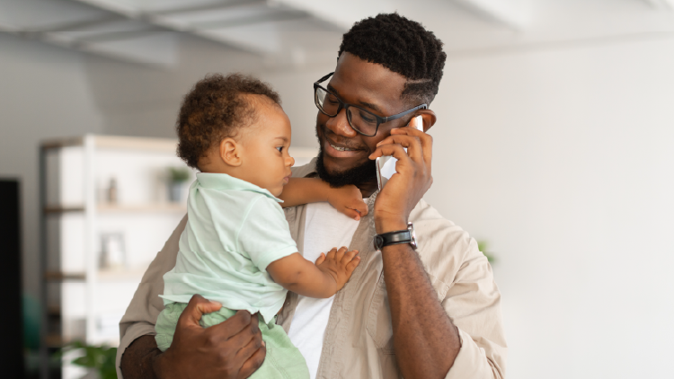 Man holding a young baby while on a cellphone