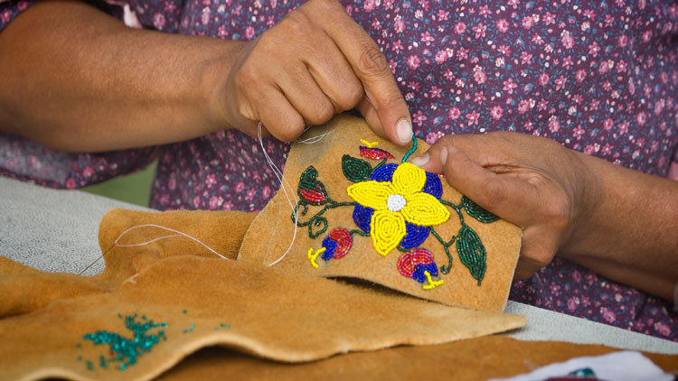 Close up of a person's hands doing beading in textile