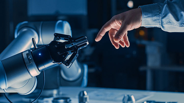 A person's arm and hand with finger pointing at a robotic arm