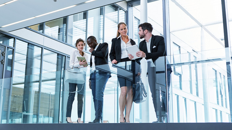 A diverse group of businesspeople looking over a raised walkway inside an office building
