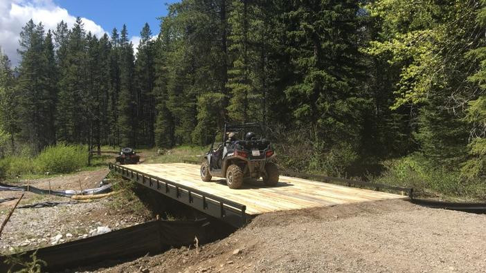 Photo of quad crossing a bridge along a designated motorized trail.
