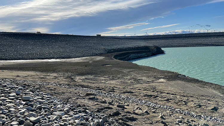 Blue water body surrounded by land, rocks and dirt