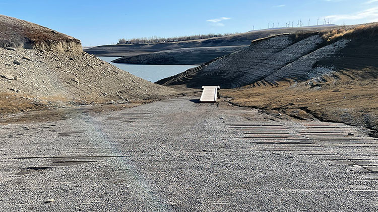 Boat launch ramp on a rocky area with hills and water in the background