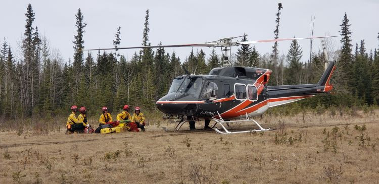 Firefighters gather near a helicopter as it's preparing to take off.