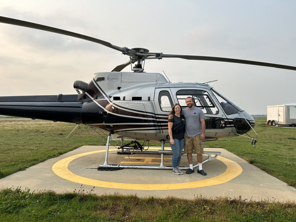 Fort McMurray's 2025 Wildfire Pledge winner, Jessica Ventham, poses with her guest, Thomas Thurston, in front of a helicopter. Jessica won an educational flight, which took place on August 31, 2025.