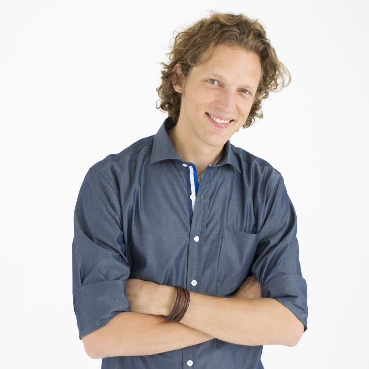 Joal stands with his arms crossed, smiling.