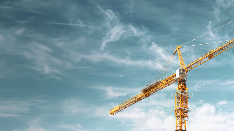 An industrial crane rises against a clear blue sky