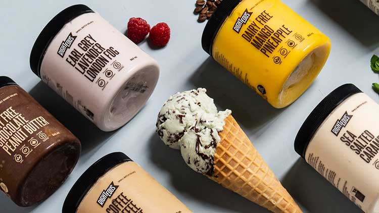 Several pints of various flavours of Righteous gelato and sorbetto laying on a grey surface with an ice cream cone in the middle.