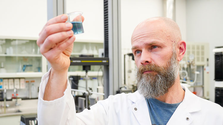 Scientist examining a beaker with liquid he is holding