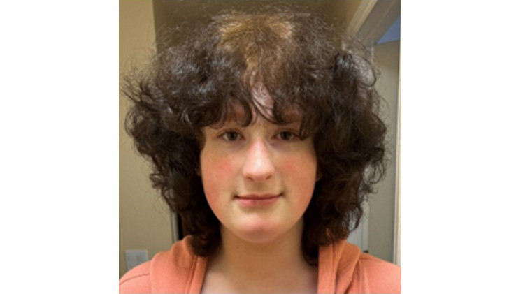 Adoption profile photo of Karina - young girl with curly brown hair in an orange top