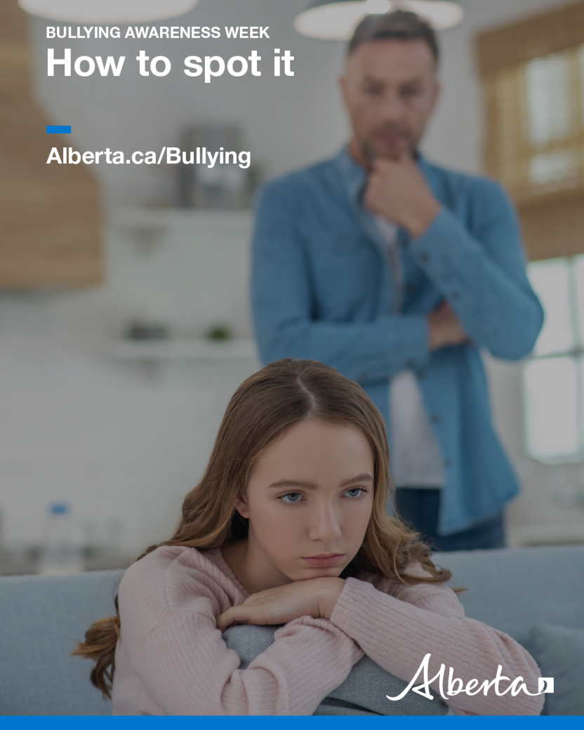 An image of a teenage girl sitting on a couch with her arms crossed and a concerned look on her face while an older man stands behind her looking worried.