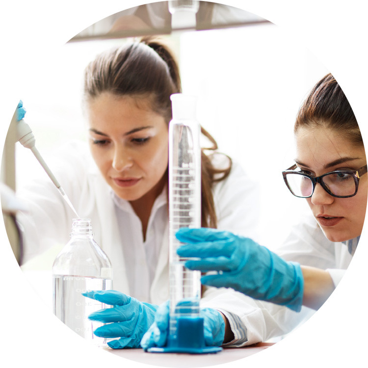 Photo of two students in a lab measuring a liquid into a tube.