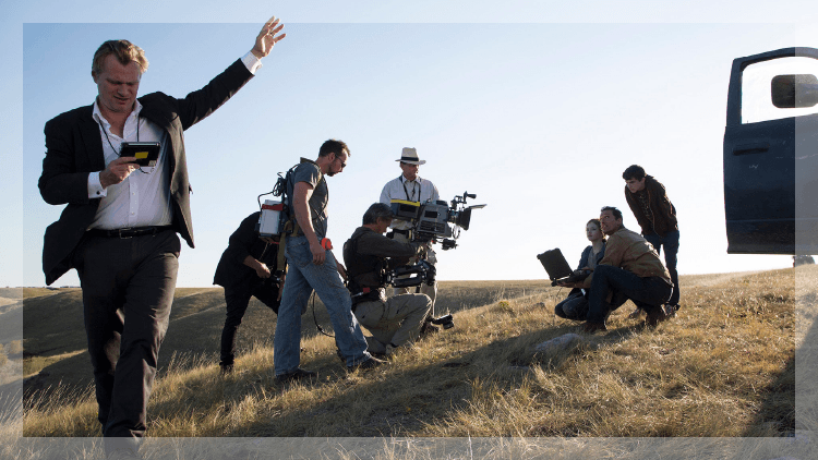 Man wearing a suit with a film crew in the background