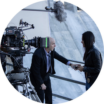 Photo of a film crew standing on a platform in front of a dam.