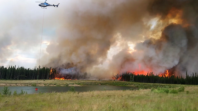 Helicoptor bucketing over a burning wildfire