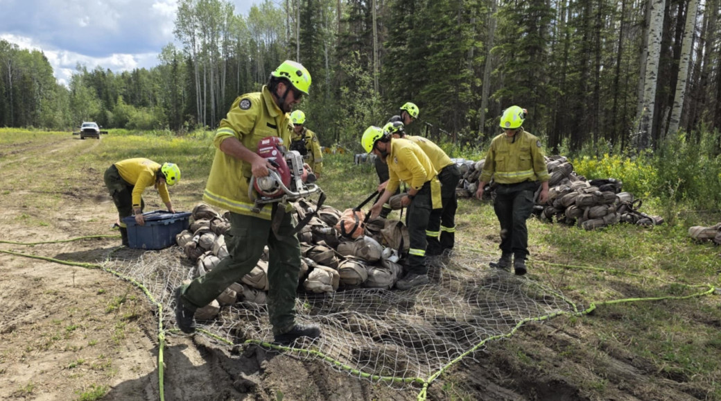 Firefighters organize pumps, hose and other equipment on wildfire HWF036 in early July 2025.