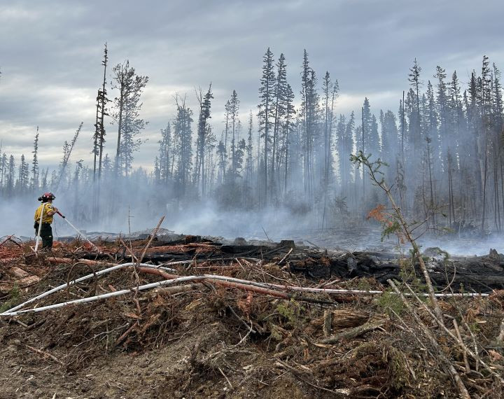 wildland firefighter running hose to a hot spot