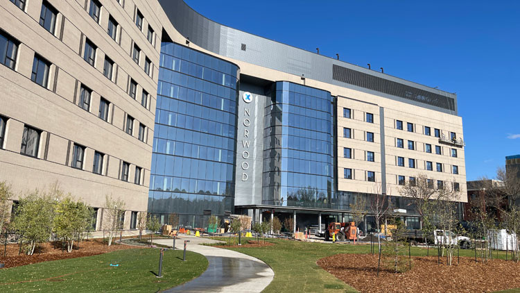 Front entrance of the Gene Zwozdesky Centre at Norwood in Edmonton: approximately 6 stories with 'NORWOOD' in large vertical  letters above the entrance flanked by a glass curtain wall on either side