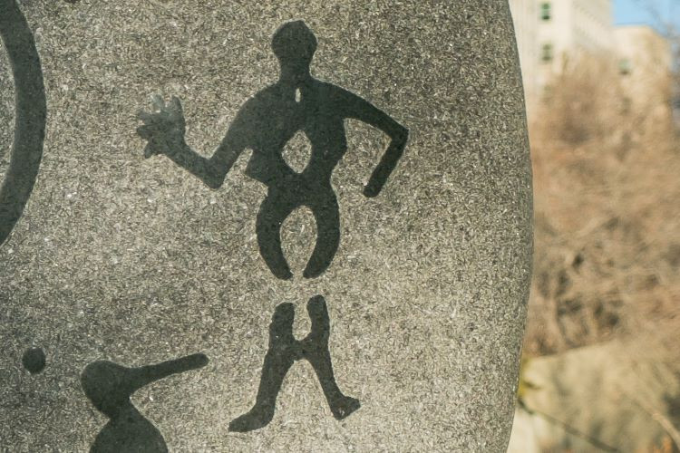 Photo of a petroglyph on the residential schools monument that depicts the breaking of water as part of the childbirth process.