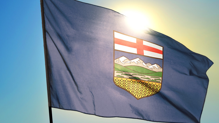 Alberta province of Canada flag waving on the wind in front of sun.