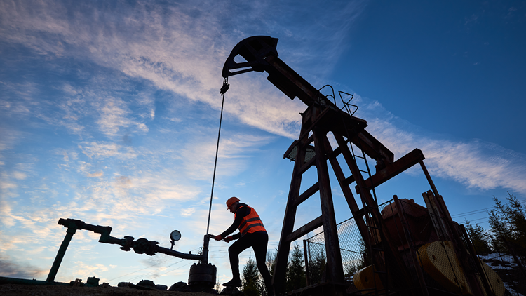 Photo of an oil derrick and a worker