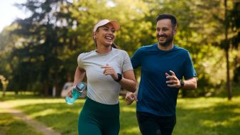 Two people jogging outdoors, smiling and enjoying a sunny day.