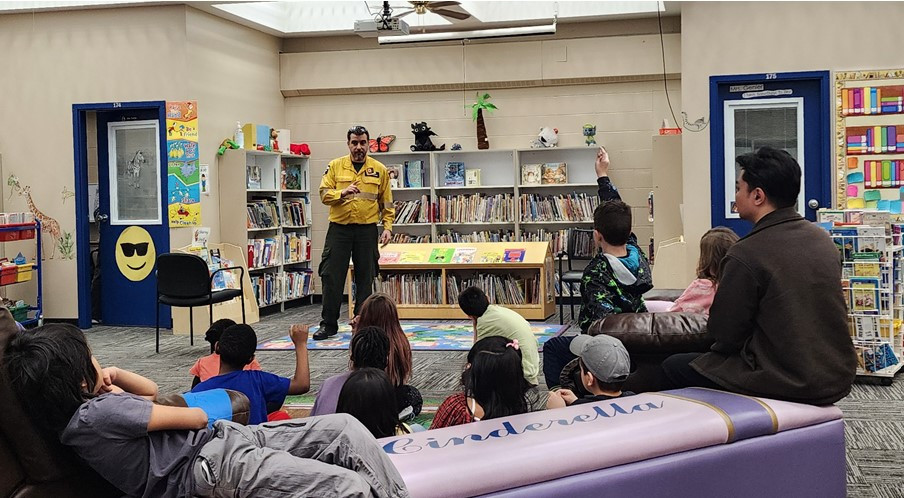 A forest officer talks about campfire safety and wildfire prevention with elementary students